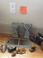 Pair of distressed white bird statues on pedestal bases with vent cover and other small figurines around them