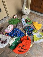 Overview of goose statue on tiled floor surrounded by assorted child-sized costume garments for multiple seasons and holidays