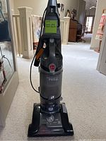 Front view of upright Hoover WindTunnel Pro vacuum cleaner with clear dirt canister and control dial on base.