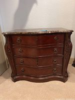 Front view of wood locking file cabinet showing four drawers with carved edges and metal handles.