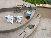 Wide view of all items including ceramic angels, iron baskets, glass orb and garden tools