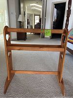 Front view of wooden quilt rack showing two horizontal bars and heart-shaped cutouts on the upright side panels.