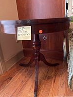 Side view of the small round wooden side table showing turned pedestal and tripod legs, with a note displaying dimensions
