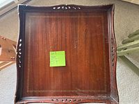Top view of the wooden side table displaying carved and pierced edges with an inlaid border on the surface