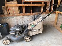 Side view of mower showing steel deck, wheels, engine cover and grass catcher bag.