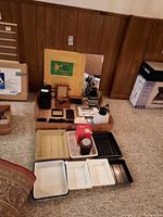 Full overview of darkroom supplies including enlarger, trays, Apollo Ferrotype Plate, film holders and tools organized on floor.