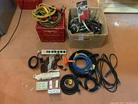Full lot overview showing extension cords, power bars, power strips, wiring, adapters, and jumper cables.
