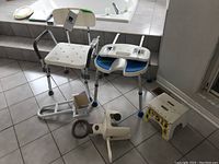 Image showing both bath chairs, two bath hand rails, and folding step stool placed on tiled floor near bathtub