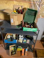 Full view of metal shelving holding various items including boxes of brushes, timers, chargers, and webbing for lawn furniture.