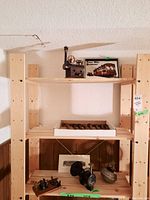 Wooden shelves displaying various railway memorabilia: a small vintage train model, framed Peter Witt Streetcar print, and railway spikes in a box along with other small train-related items on lower shelves.