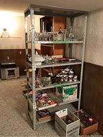 Metal shelving unit loaded with various household items like glasses and boxes, shown from front angle