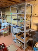 Side view of metal shelving unit filled with boxes and hardware items, showing adjustability and shelf contents.