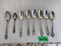 Eight spoons arranged in row on white background with green 'Sterling' label