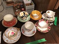 Overview of all 7 tea cups and saucers showing different colors and patterns