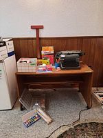 Vintage Olympia typewriter on wooden desk surrounded by notebooks, boxes of paper clips, pencils in pencil holder, and other office supplies.