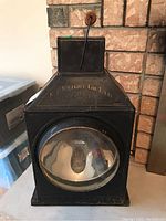 Front view of black metal lantern with large convex glass lens showing E.T. Wright Co. Ltd. marking.