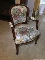 Front and side views of the wooden frame armchair with floral upholstery showcasing the carved wood and padded armrests covered in fabric.