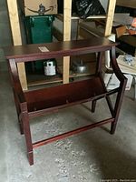 Front view of the wooden book/magazine stand showing the slanted front holder and flat top surface