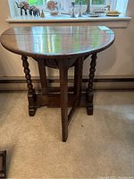 Side angle photo showing table with one drop leaf folded down and barley twist legs.