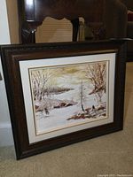 Full view of the framed oil painting showing the winter landscape and the dark wood frame.