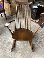Front view of the solid wood rocking chair showing the slat backrest and curved armrests.