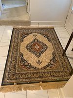 Top view of beige, navy, and burgundy oriental-style rug with central medallion and fringe on the ends.
