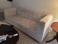Front right angled view showing full sofa profile, tufted back, arm, seat cushion and brass-look base
