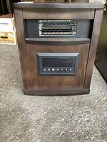 Front view of the Konwin wood encased space heater showing the heating element grill and control panel with buttons.