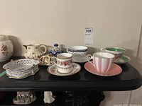 Full view of all items on black surface showing cups, saucers, creamer, butter dish, and Royal Crown Derby turtle figurine.