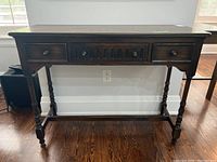 Front view of oak hall table showing three drawers and turned legs