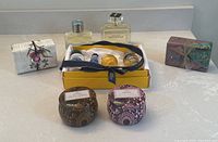 Lot overview showing cologne bottles, decorative jars, wrapped soaps, and L'Occitane gift box with products.