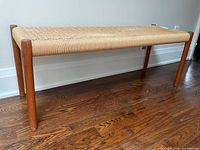 Overall view of bench: full length showing teak legs and woven cord seat.