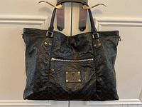 Full front view of black embossed leather tote bag hanging from door handles