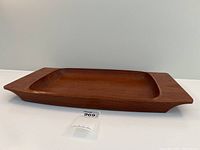 Side view of large teak serving tray showing smooth sculptural form and tapered handles.