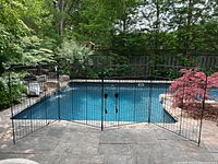 Four hinged metal lattice panels arranged in an arc in front of a pool