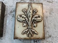 Front view of Sid Dickens Heraldry tile with raised fleur-de-lis design