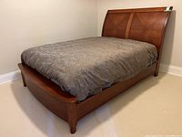 Full view of queen-sized walnut wood sleigh bed frame with mattress