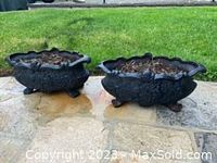 Pair of black cast iron planters side by side on stone patio
