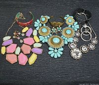 Photo of entire jewelry lot showing necklaces, bracelet and earrings on black surface
