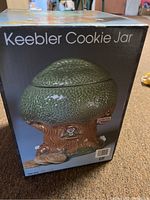 Photo showing the Keebler Cookie Jar in its original box with detailed image of the treehouse design