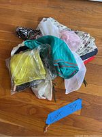 Lot of scarves and handkerchiefs piled on wood floor with visible textures and colors