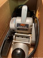 Skil Model 100 planer inside box, showing top view, Skil badge, front knob and power cord coiled