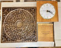 All three items together on a table showing the carved wall decor, clock, and trimming board.