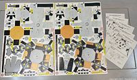 Photo showing two large printed punch-out sheets for Gulf Oil 1960's lunar module kits with geometric color patterns, and five assembly instruction sheets.
