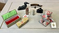 Overview photo showing all items in lot on table including fabric hippo with tag, carved soapstone stamps and boxes, soapstone bird, resin Haida whale, and small carved wooden whale.