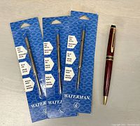 Pen with 3 unopened Waterman ballpoint pen refill cartridges in blue ink medium point.
