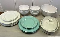 Photo showing full set of white and jade green dishes, including plates, bowls, large popcorn bowl, and covered casserole dish.