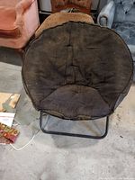 Top-down view of a round hammock chair with worn black fabric seating on black metal frame in a room with other furniture.