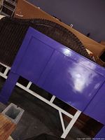 Photo of the full size brown headboard showing its rectangular paneled design, brown paint with some wear, leaning against a surface in a room.