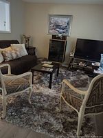 Living room featuring a silver-grey plush area rug placed in front of a brown sofa and between two upholstered chairs. The rug is the focus, shown fully on the floor, with a texture that looks very thick and soft.